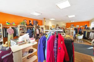 Farbenfroher Verkaufsraum mit Kleidung und Haushaltswaren für Arbeitsmarktintegration.