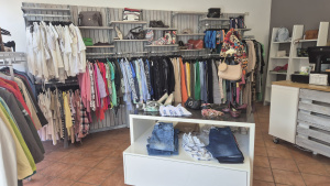 Second-Hand-Verkaufsraum mit Kleiderständern, Taschen, Schuhen und einem Verkaufstresen